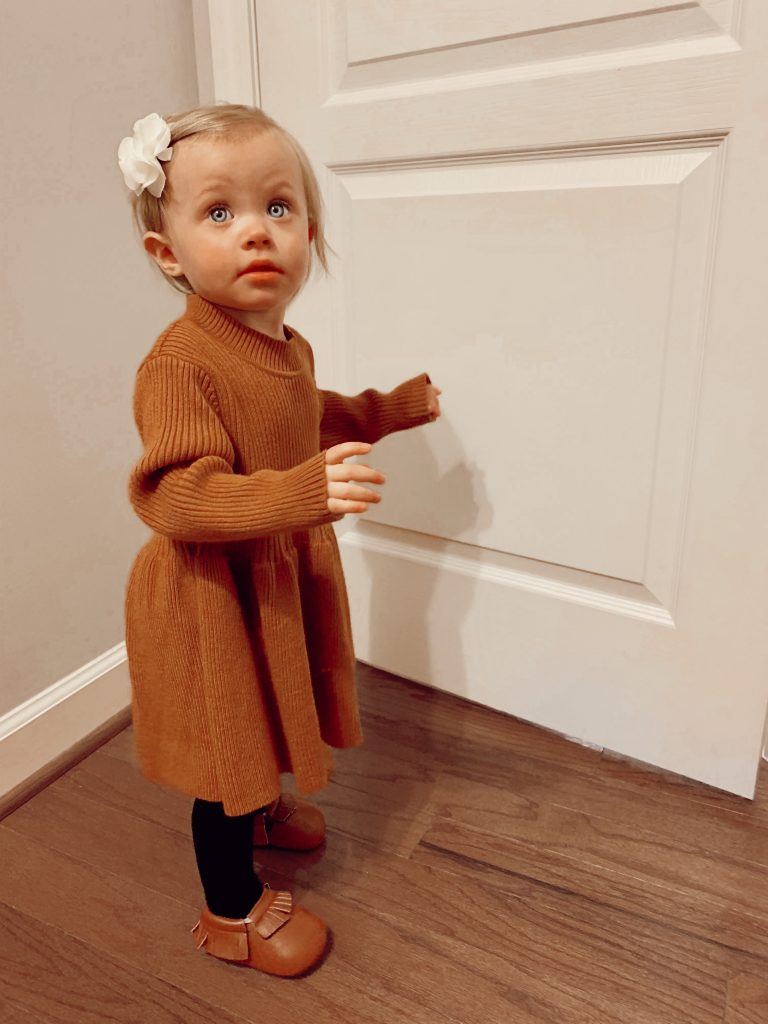 Affordable Kids Fashion | Aliexpress Outfit Review by Babies, Love, and Lattes, a motherhood and lifestyle blog by North Carolina blogger Jessica Linn.
A baby girl wearing a brown sweater dress, black stockings, brown moccasins, and a floral chiffon hair clip all from Aliexpress.